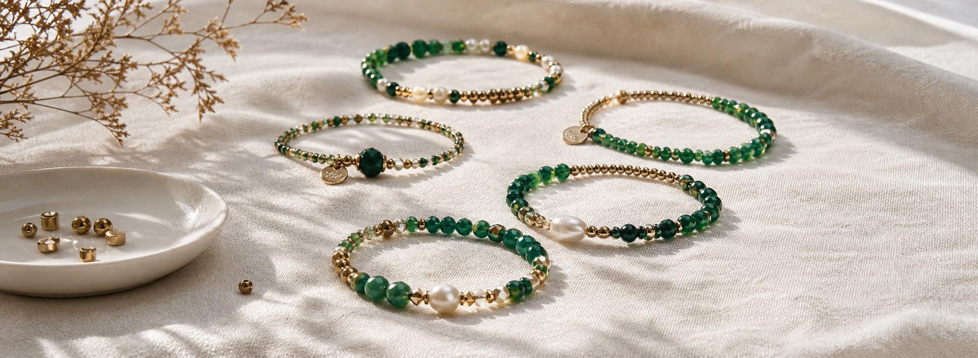 Handmade emerald and gold beaded bracelets arranged on ivory linen